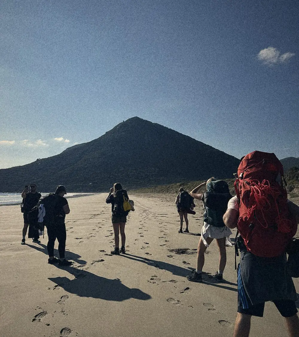 A group walking along the beach on a coastal hike